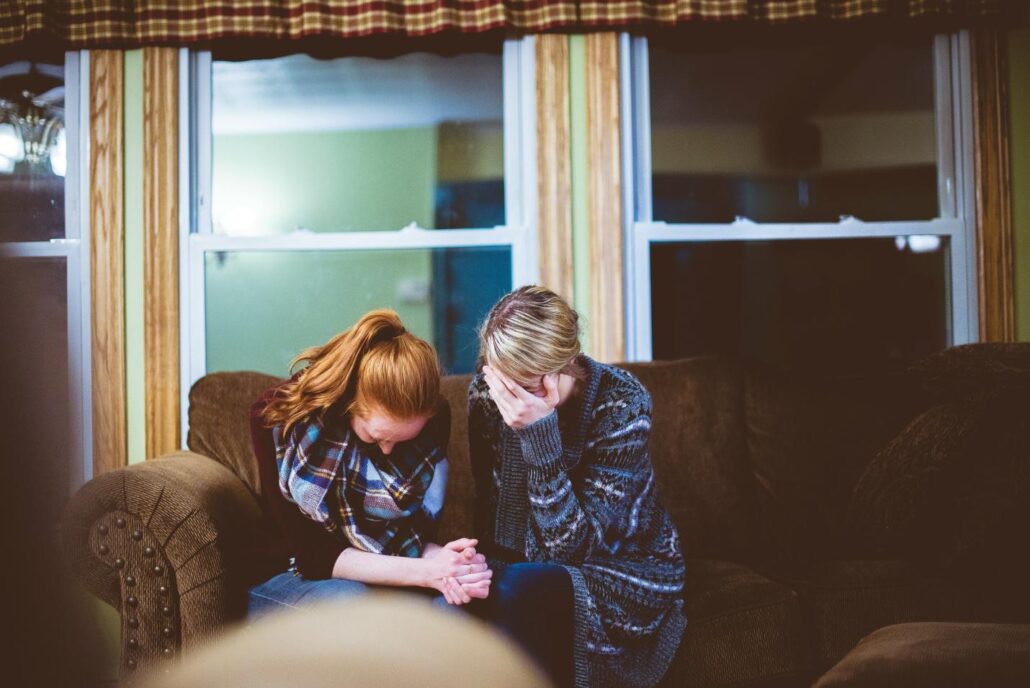 Two people holding hands and sobbing together.